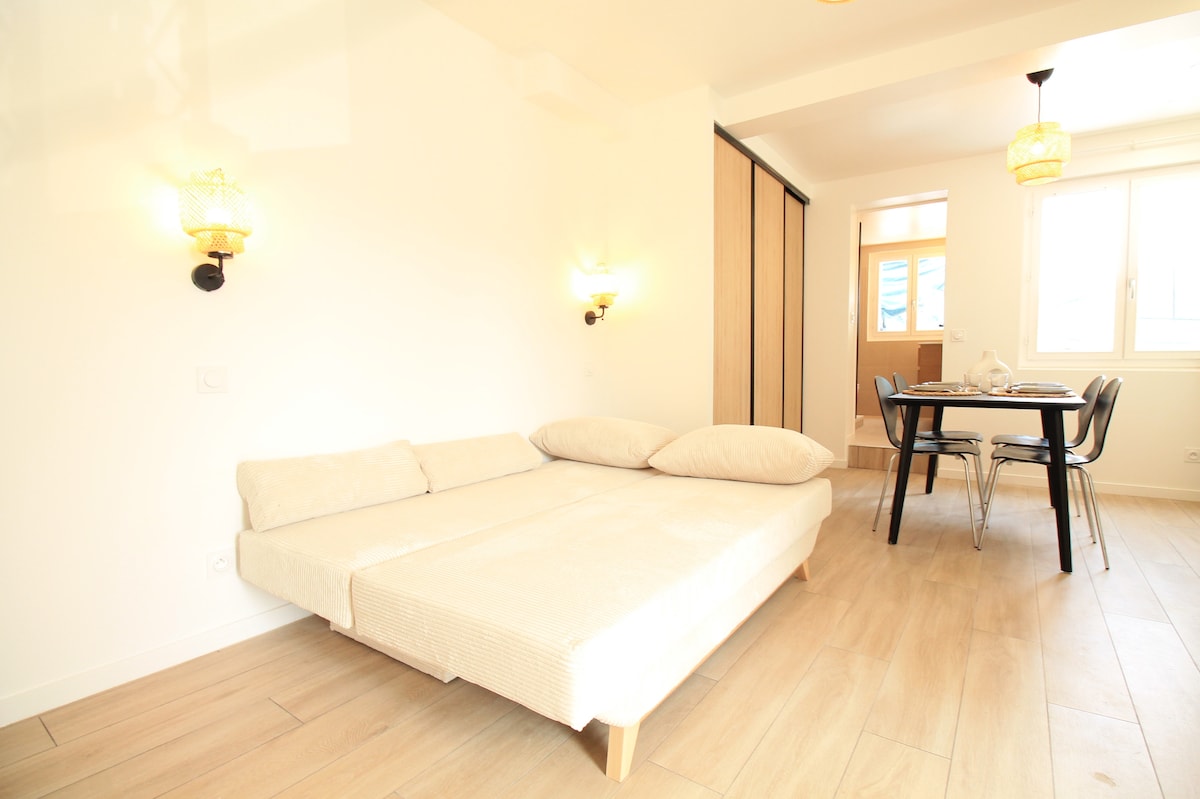Chambres — Lit blanc spacieux, table noire, luminosité naturelle généreuse