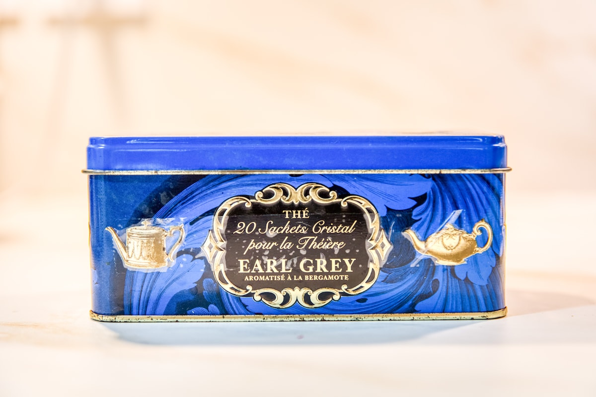 Et aussi — Boîte de thé Earl Grey, surface claire, lumière douce