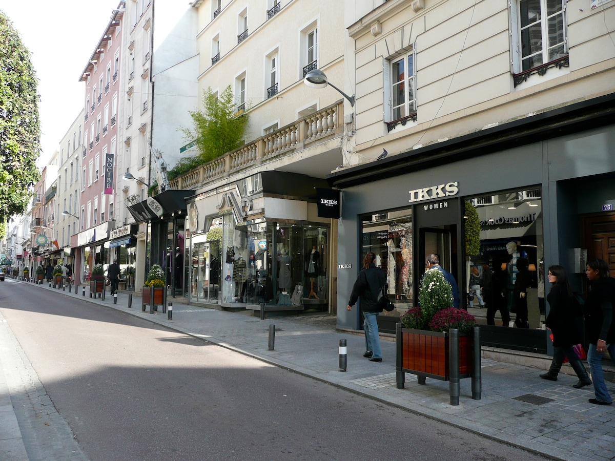 Extérieur — Rue commerçante avec boutiques et immeubles parisiens