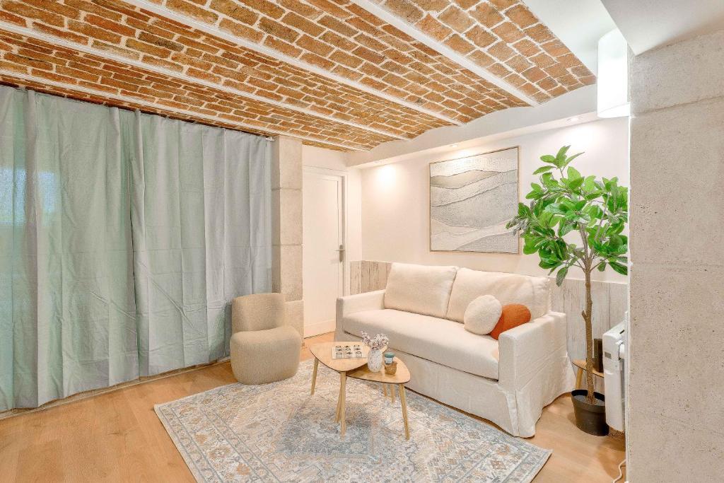 Salon & séjour — Canapé blanc, fauteuil beige, plafond briques apparentes