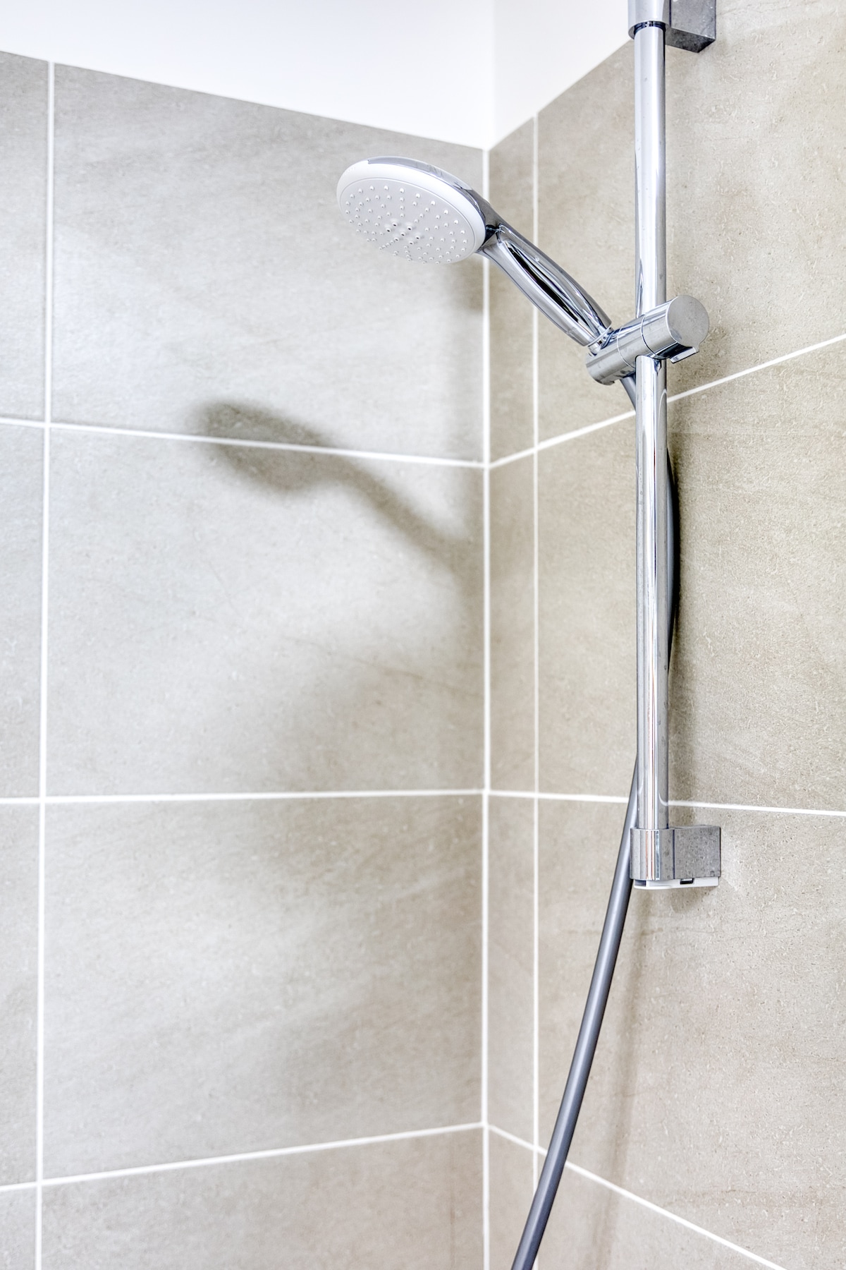 Salle de bain — douche carrelée beige, pommeau chromé moderne