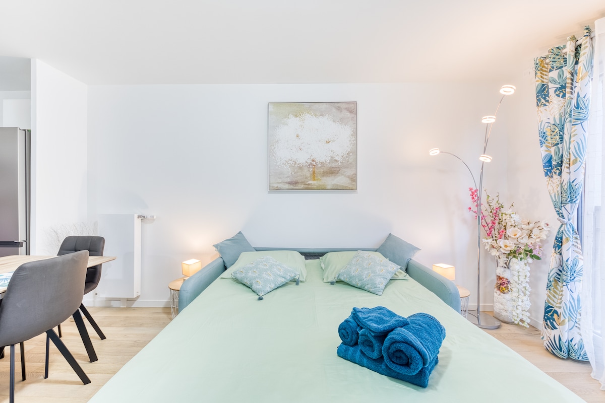 Chambres — Lit bleu ciel, mobilier minimaliste, lumière douce et chaleureuse