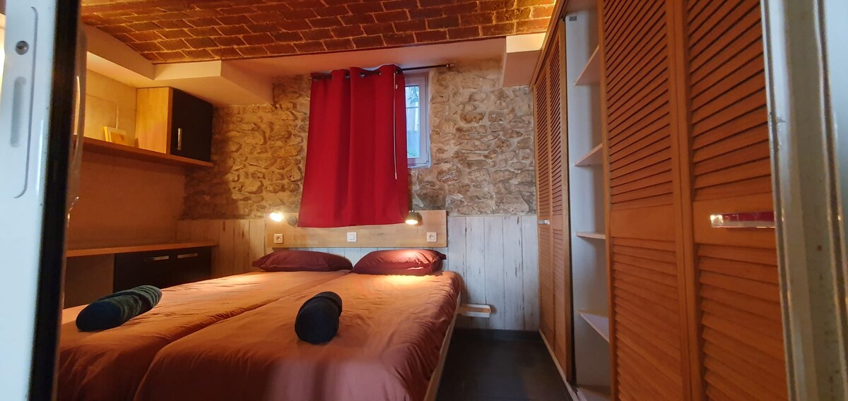 Chambres — Lit double orange, mobilier bois, lumière chaude, rideau rouge