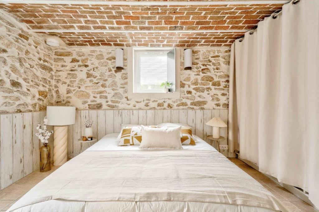 Chambres — Lit blanc, murs pierre rustique, poutres apparentes, ambiance chaleureuse