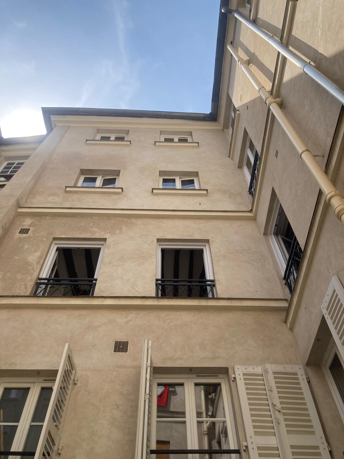 Extérieur — Façade beige, fenêtres régulières, architecture classique parisienne
