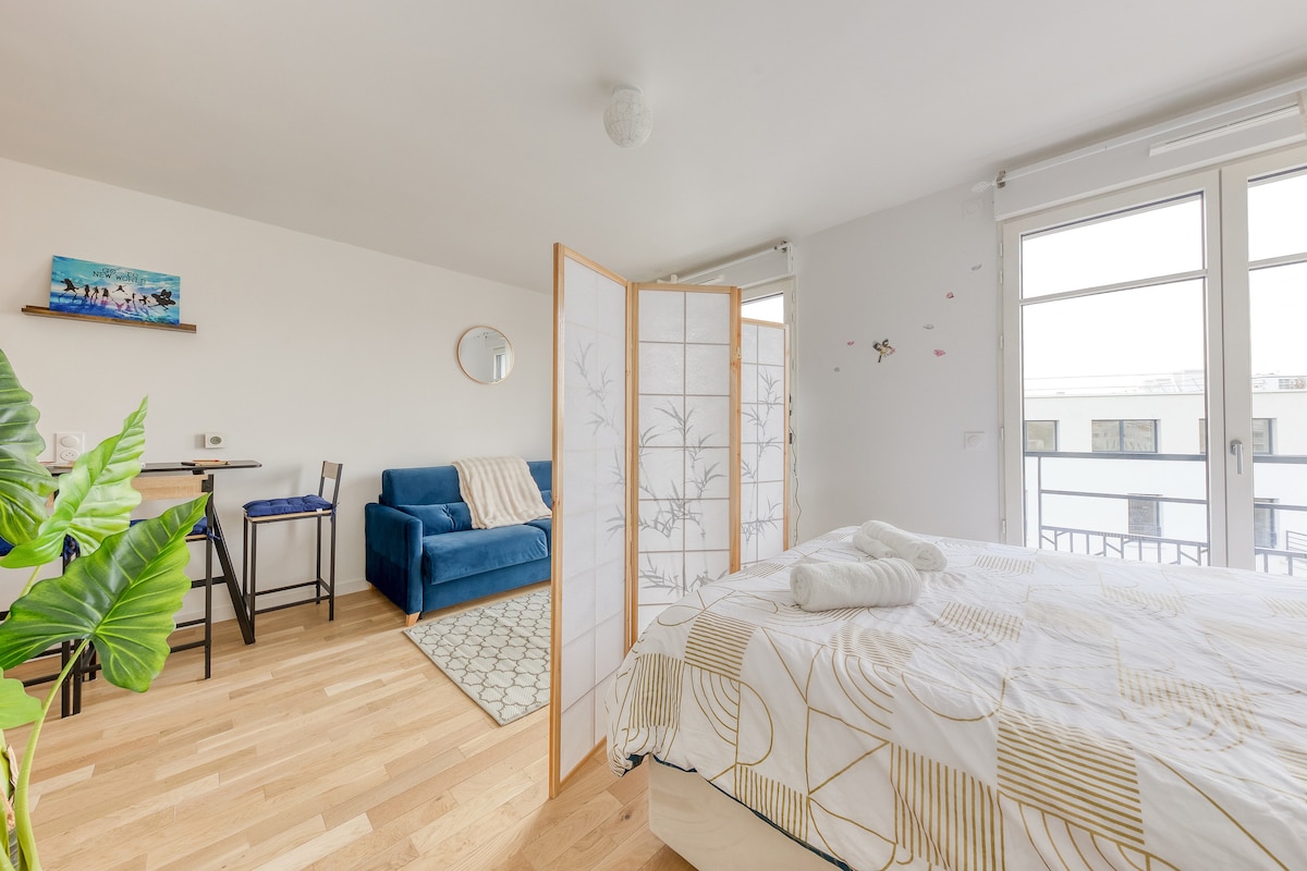 Chambres — Lit lumineux, séparation bois, fauteuil bleu, plantes vertes