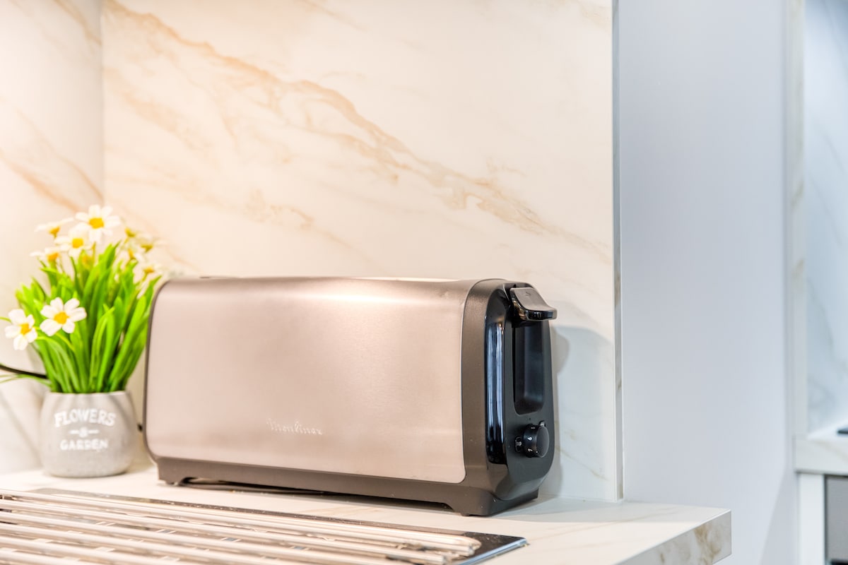Cuisine — Comptoir marbre clair, toaster chromé, fleurs blanches décoratives