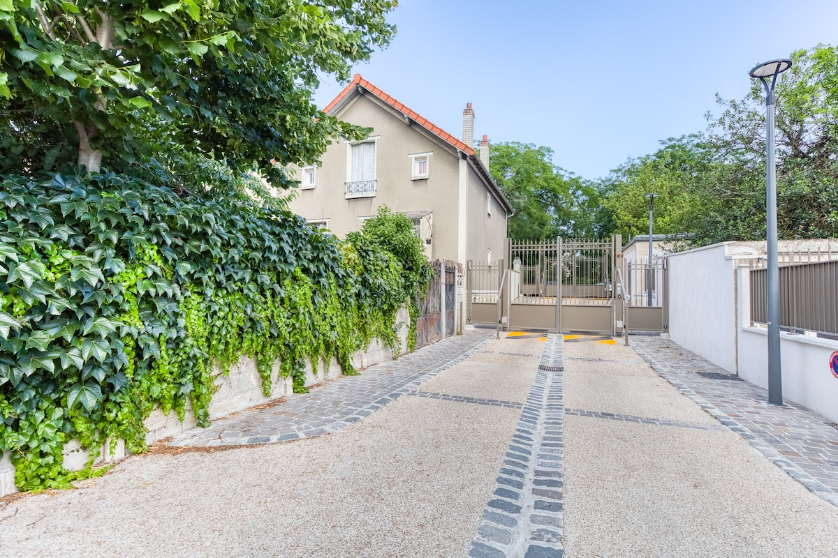 Extérieur — Allée pavée, portail métallique, lierre verdoyant