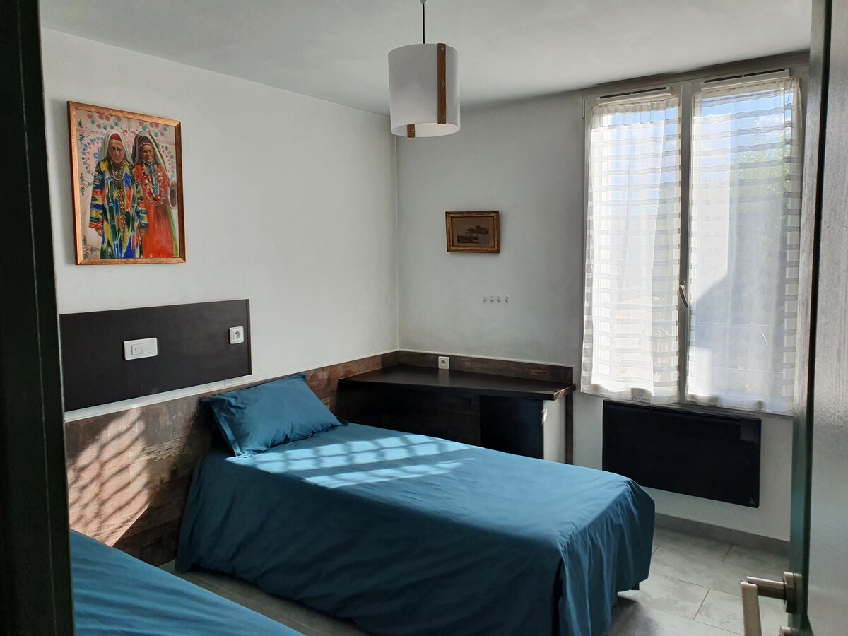 Chambres — Lit bleu, bureau noir, lumière naturelle abondante