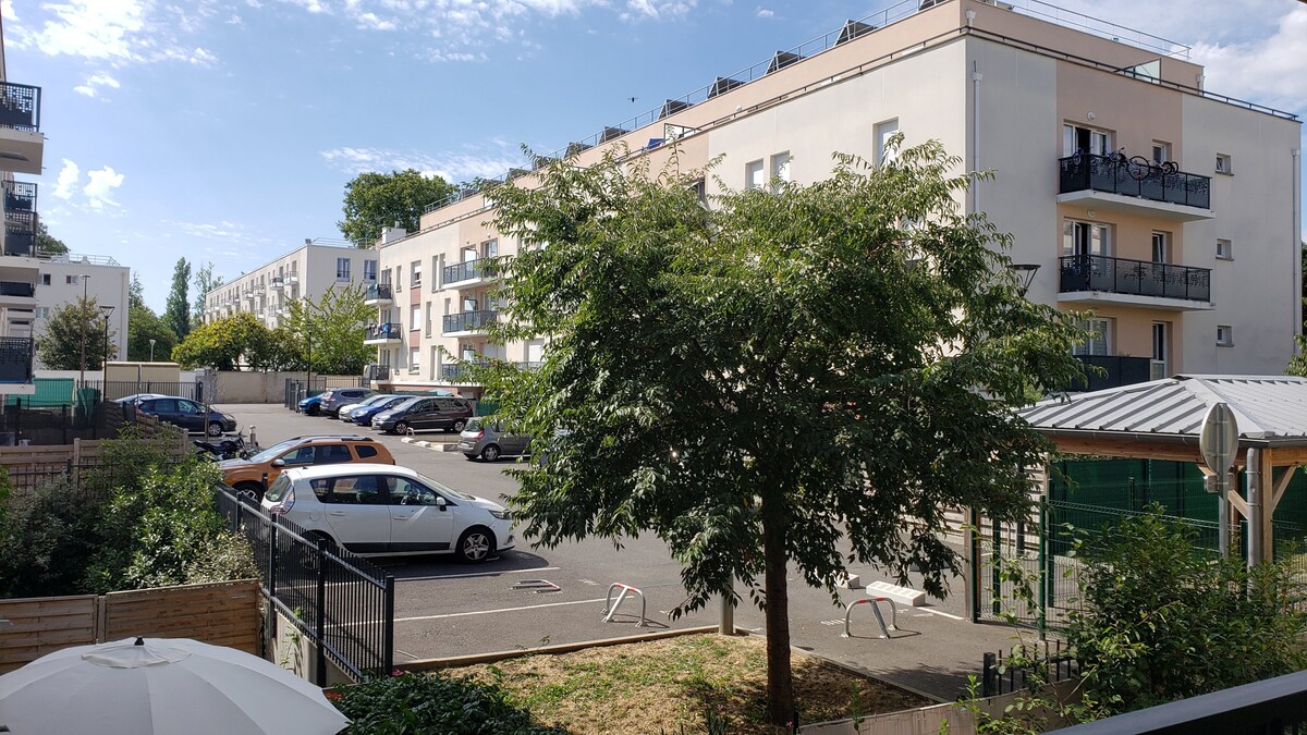 Balcon & terrasse — Terrasse ensoleillée avec vue parking, parasol blanc, végétation verdoyante