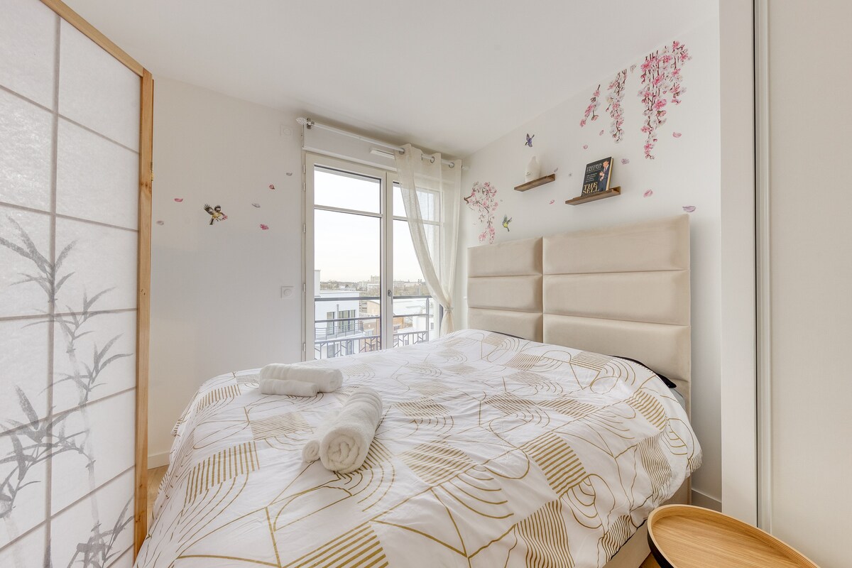 Chambres — Lit beige, décoration florale murale, lumière naturelle, minimaliste