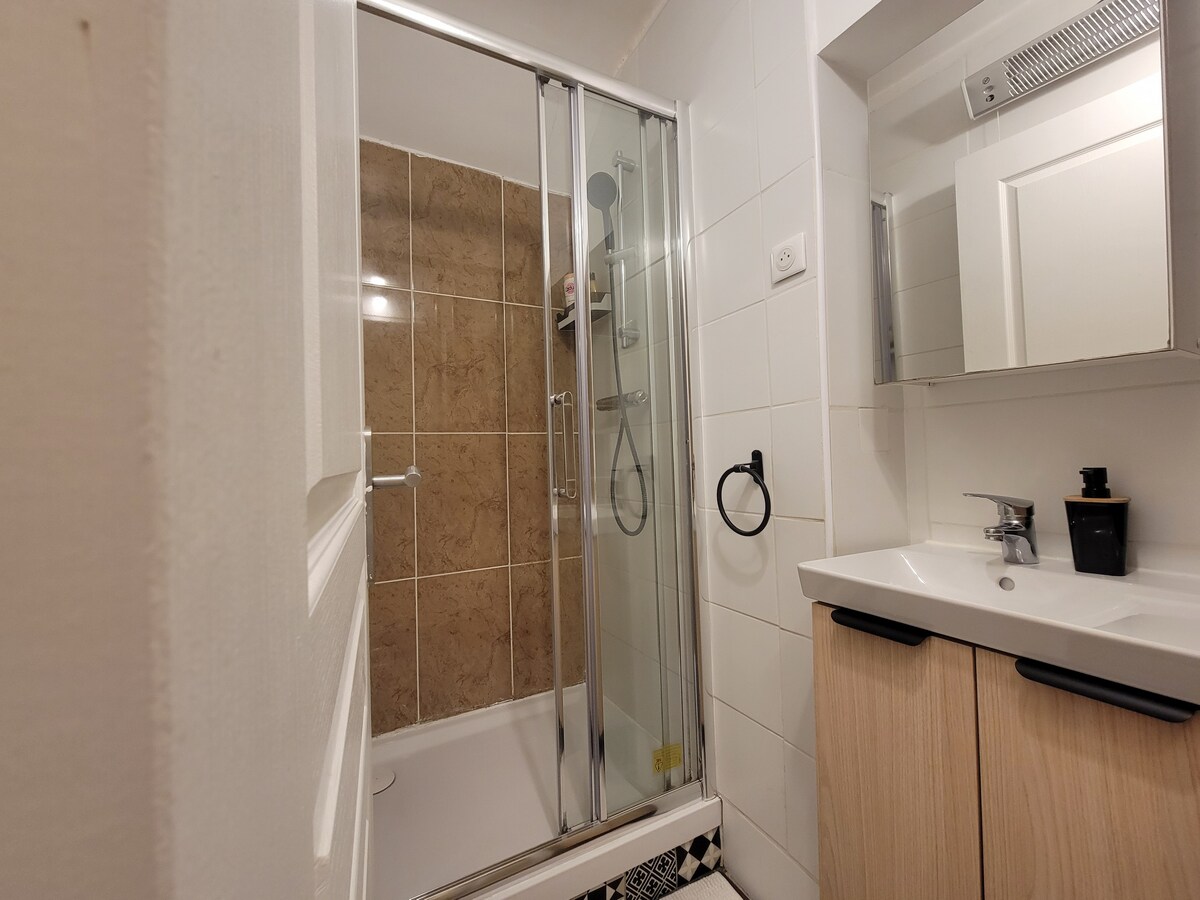 Salle de bain — Douche vitrée, lavabo bois, miroir, carrelage blanc