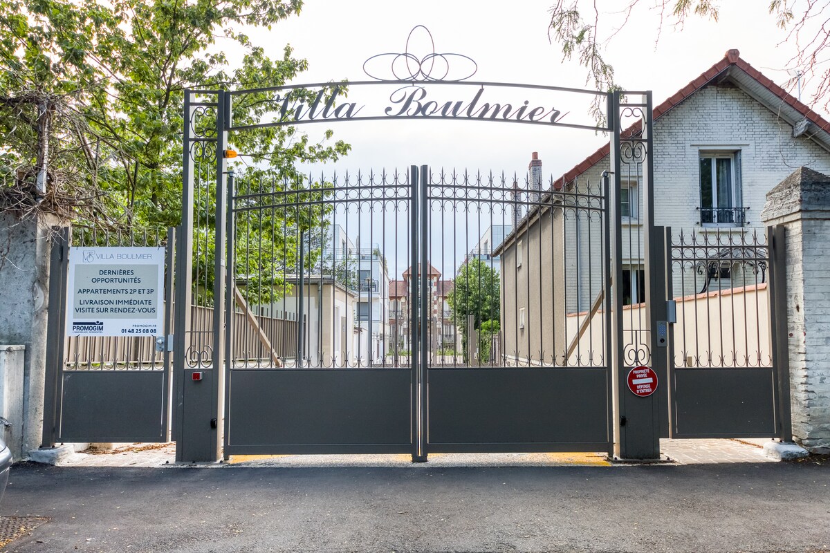 Extérieur — Portail noir ornementé, allée pavée, bâtiments résidentiels