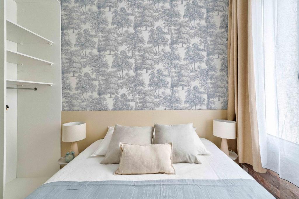 Chambres — Lit élégant, papier peint motifs arbres, lampes blanches