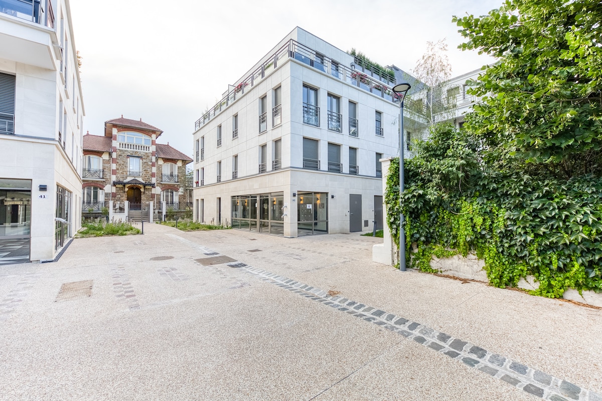 Extérieur — Cour pavée moderne entourée bâtiments, végétation luxuriante