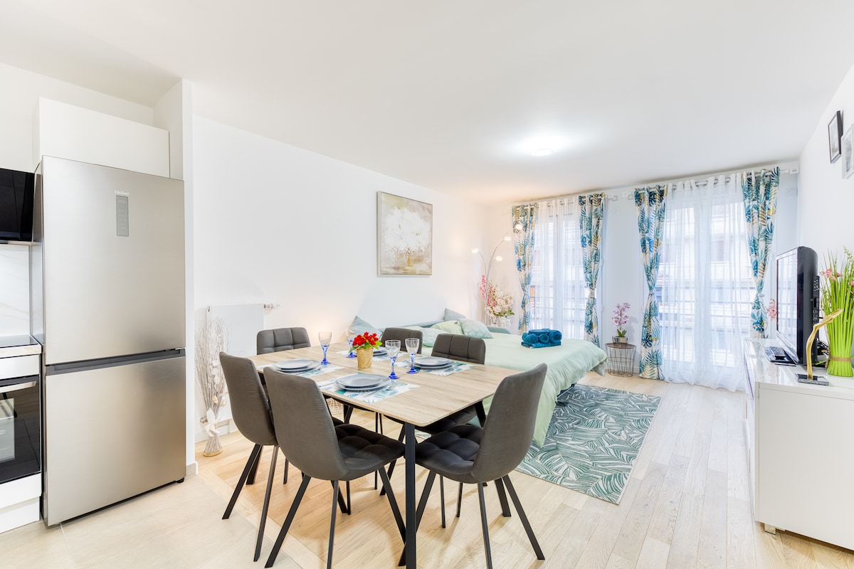 Salon & séjour — Espace lumineux, table à manger avec chaises grises, canapé lit au fond