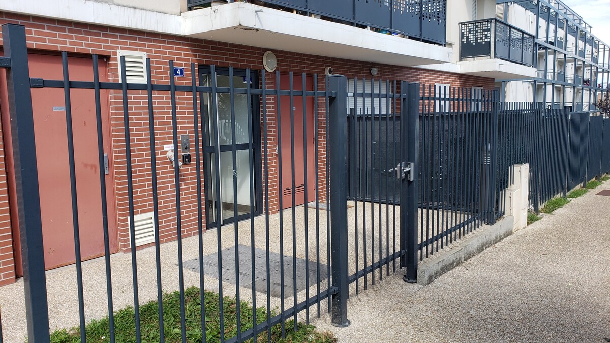 Extérieur — Entrée extérieure avec portail noir, brique rouge