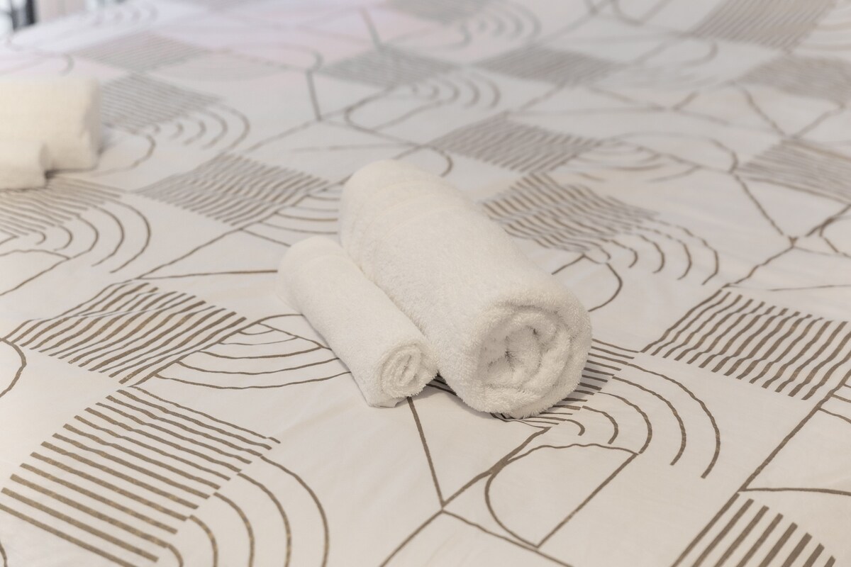 Chambres — Lit avec draps blancs et motifs géométriques gris